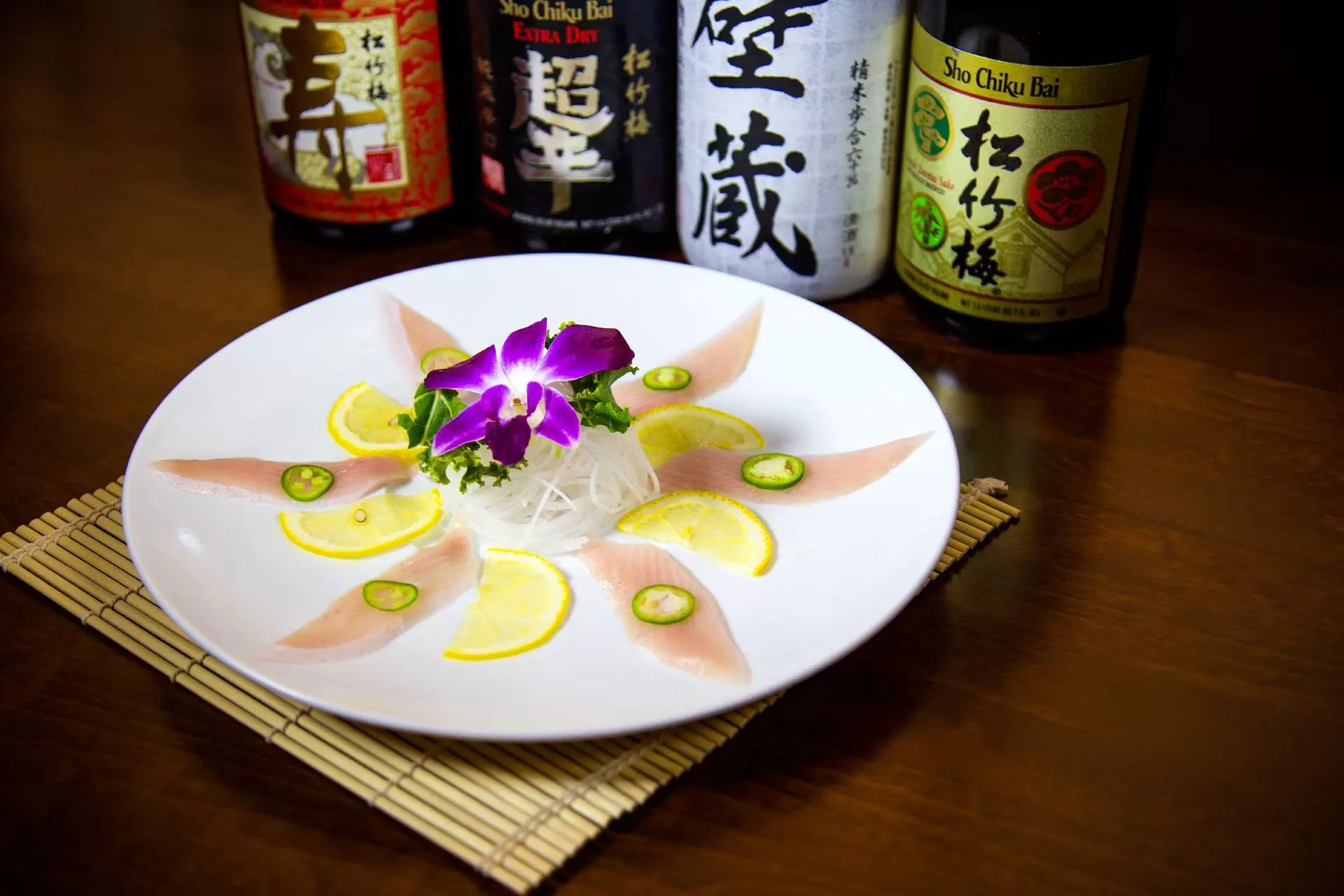 Artfully arranged white fish sashimi garnished with orchid and fresh lemon slices at Midori Sushi Of Highland Park, a Japanese Restaurant in Highland Park